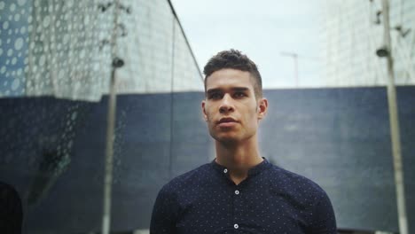 well-dressed entrepreneur businessman young attractive trendy man looking into his own reflection on a modern building window and then looking straight to the camera in slow motion