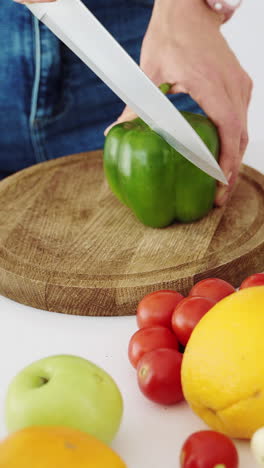 slices of green sweet pepper. the girl cuts pepper with a knife in the kitchen. vertical video