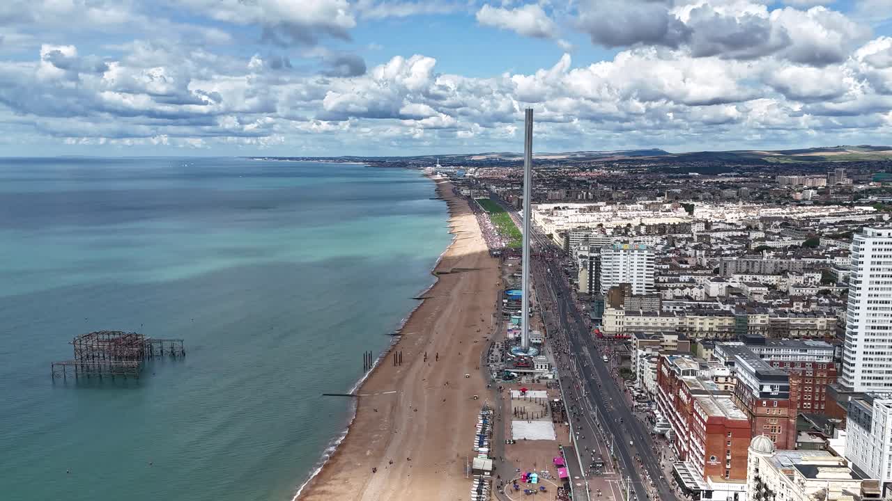Timelapse aerial of Brighton Pride 2025 along the seafront, with clouds forming overhead and colourful crowds moving below, appearing like tiny ants in a vibrant coastal celebration