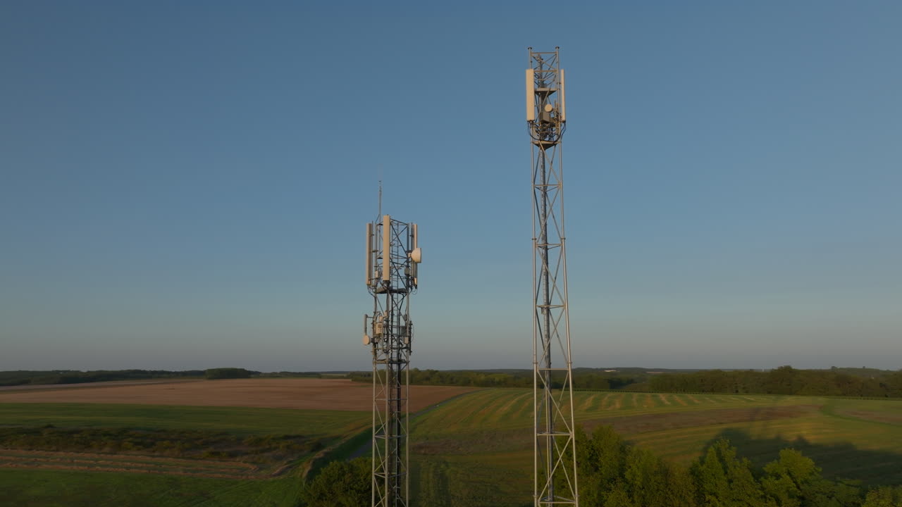 dos torres de radio en el medio de las tierras de cultivo durante el amanecer, órbita aérea