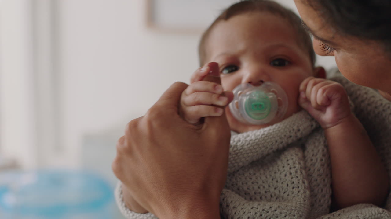 mother holding baby at home calming tired newborn gently soothing restless infant sucking on pacifier loving mom enjoying motherhood