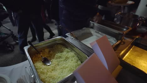 en un buffet al aire libre se coloca una cuchara en un recipiente con comida