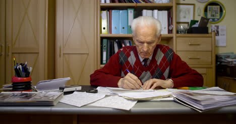 senior businessman writing on paper at table in office 17