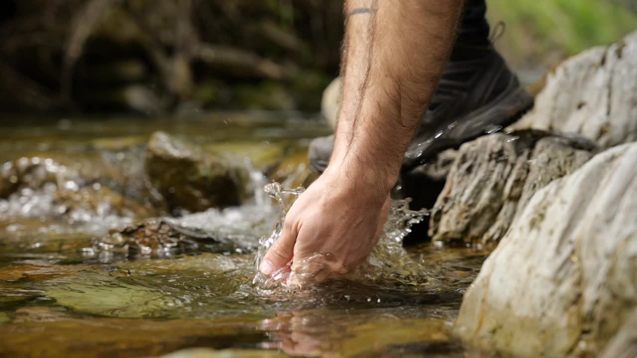 Washing hands into stream of water in natural landscape