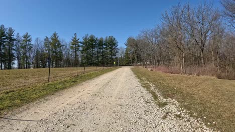 pov - driving a trail vehicle on graveled lane and turning onto groomed trail through timber that leads to a home