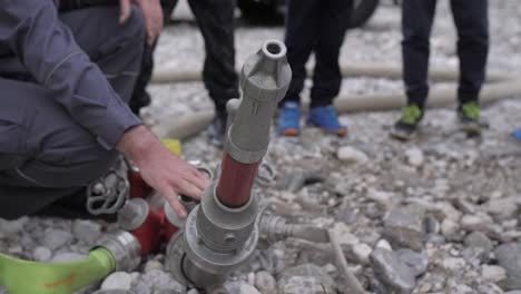 fire-fighter-showcasing-fire-hose,-children-watching-in-background,-closeup-slowmo