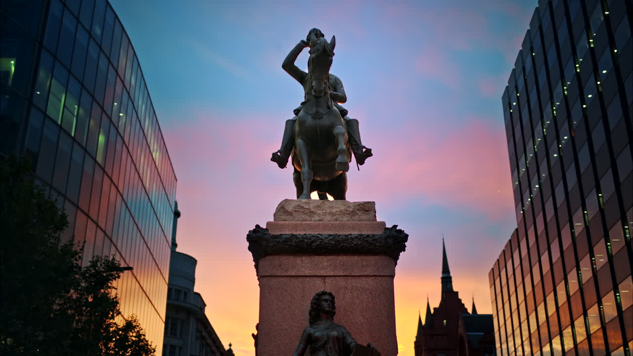 Prince Albert Equestrian Statue at sunset in London, United Kingdom. Modern buildings around, the sunset sky on the background