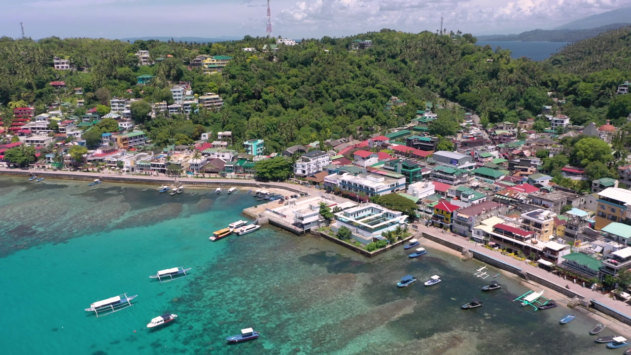 A stunning drone video captures Puerto Galera and Sabang Bay with turquoise waters, boats, and diving schools, showcasing the tropical beauty of this famous Philippine destination.