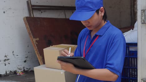 young asian delivery man checking package on tablet before sending to the customer