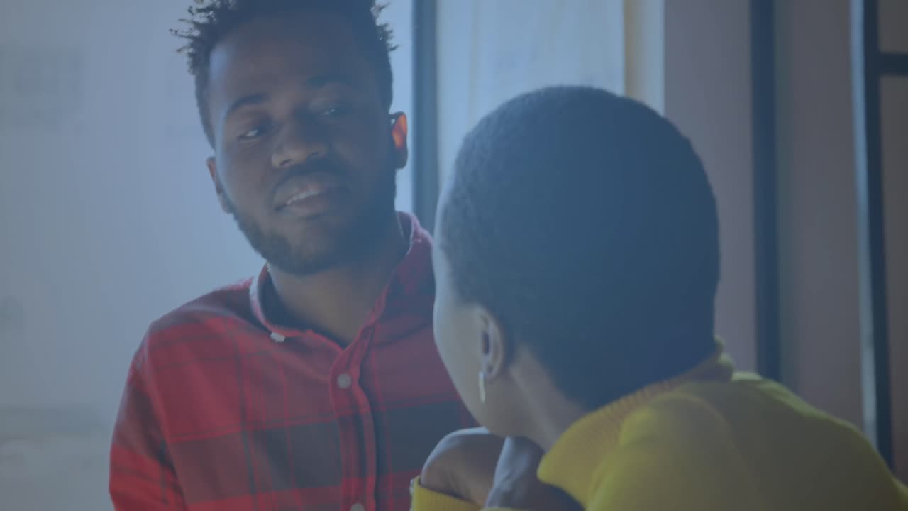 animación de iconos digitales girando sobre un hombre y una mujer afroamericanos discutiendo en la oficina.