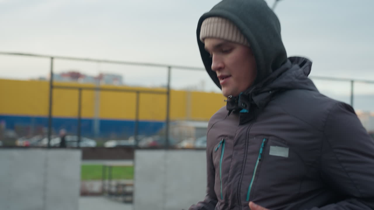 스포츠 경기장에서 운동과 조정에 초점을 맞추며 축구를 적극적으로 훈련하는 운동 선수, 배경에는 체인 같은 울타리, 입구 및 도시 풍경이 있습니다.