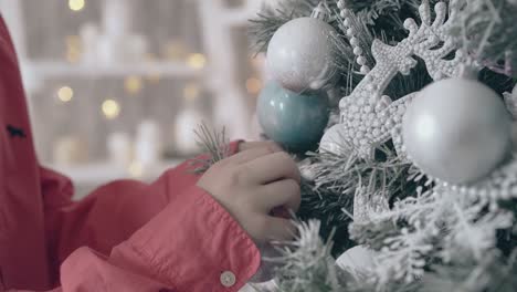 boy hands in red shirt decorate silver christmas tree