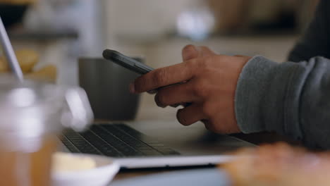 close up hands using laptop computer working at home in kitchen typing email checking messages on smartphone enjoying modern wireless communication technology