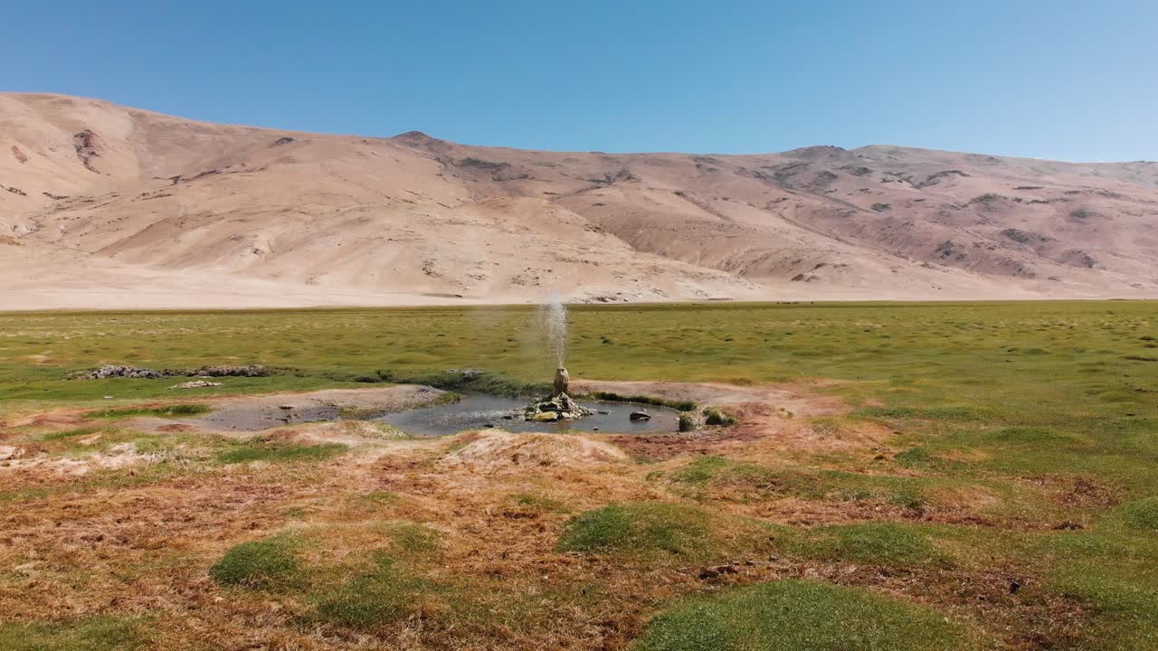 Geyser in a Field with Mountains