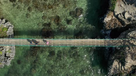 ascending aerial of crossing island suspension bridge over clear tropical waters 4k