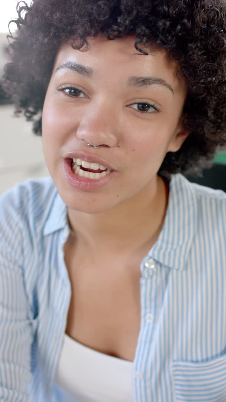 Vertical video of portrait of biracial casual businesswoman having video call in slow motion