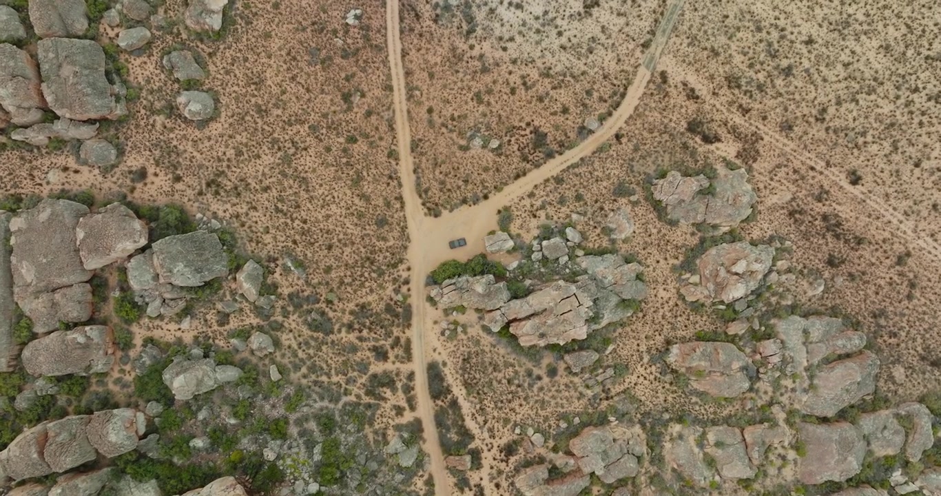 Drone flies in bird's eye view over desert landscape and rock formations in Cederberg Wilderness Area in South Africa empty road in the desert drone turns slightly downwards -off-road vehicle standing