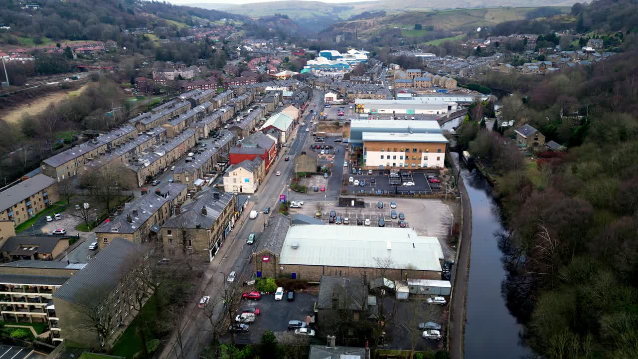 toma de dron de halifax rd en todmorden, noroeste de yorkshire, esta toma de dron de movimiento lento muestra la calle tranquila con tiendas y zonas verdes, con un hermoso canal en el lado derecho