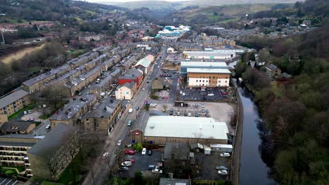 drone shot of halifax rd in todmorden north west yorkshire , this slow moving drone shot shows the quiet road with shops and greenery , with a lovely canal down the right hand side