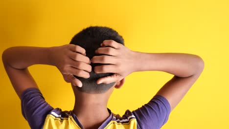 niño adolescente rascándose la cabeza contra un fondo negro
