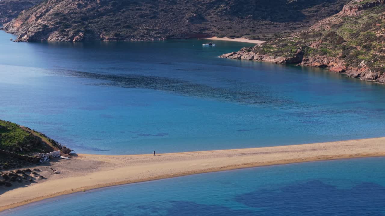 Kolona Beach from above showing curved sandbar with turquoise bays and steep shoreline surrounds, aerial tracking right