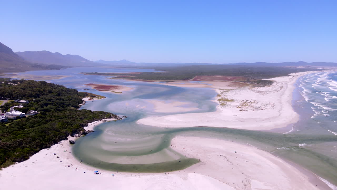 해수욕장 방문객들은 클라인 강 입구의 은 물을 즐기며 바다로 흘러들어갑니다.