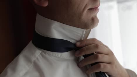 handsome groom fixes his tie. wedding morning. businessman. slow motion