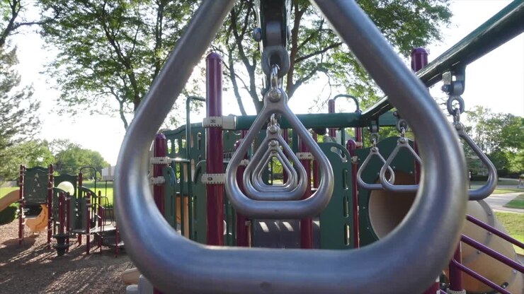 Kids rings swaying lightly in a playground, medium shot symmetric
