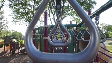 Anillos-Para-Niños-Que-Se-Balancean-Ligeramente-En-Un-Patio-De-Recreo,-Tiro-Medio-Simétrico