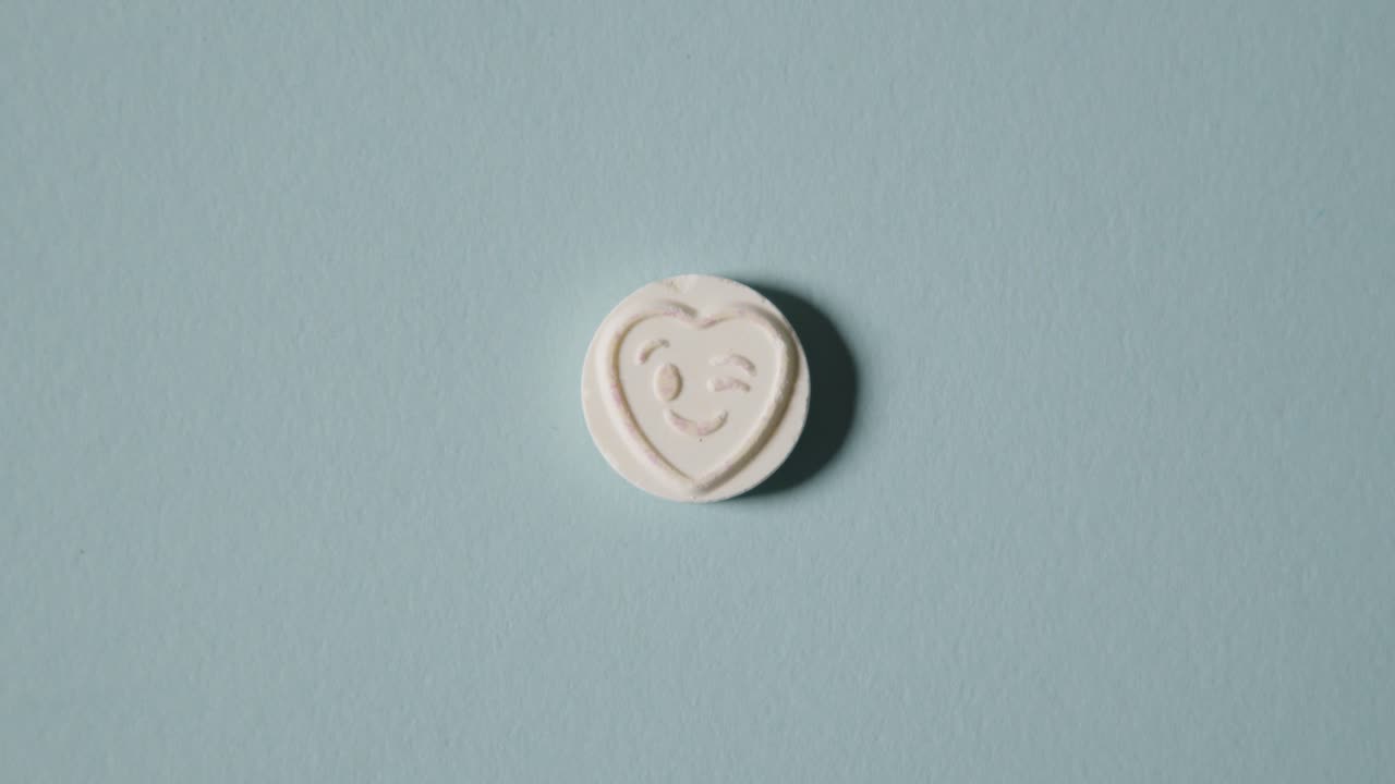 파란색 배경에 윙크하는 이모티콘으로 하트 사탕을 손에 들고