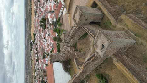 Vertical-video-of-Mourao-fortified-walls-fortress,-tilt-down-view,-Portugal