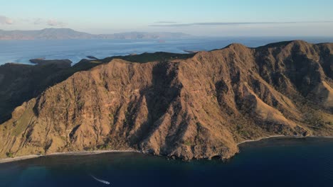 high altitude drone flying towards the ridge of a dry and rocky island