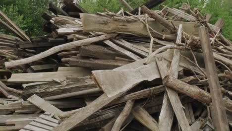 Pan right view of leftover planks and tree branches stacked in pile in yard