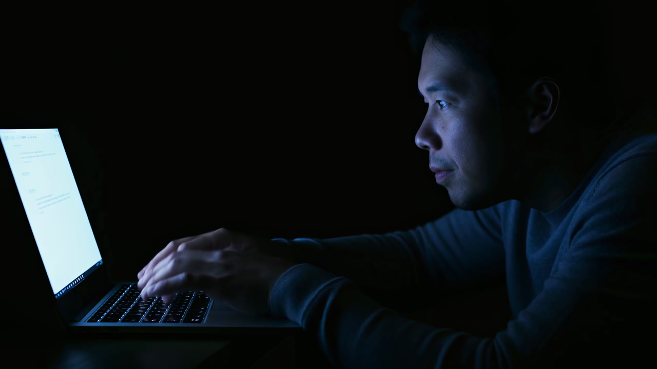 Man At Laptop Under Blue Light, Focused On Code And Documents, Nocturnal Security Research And Debugging, Dark