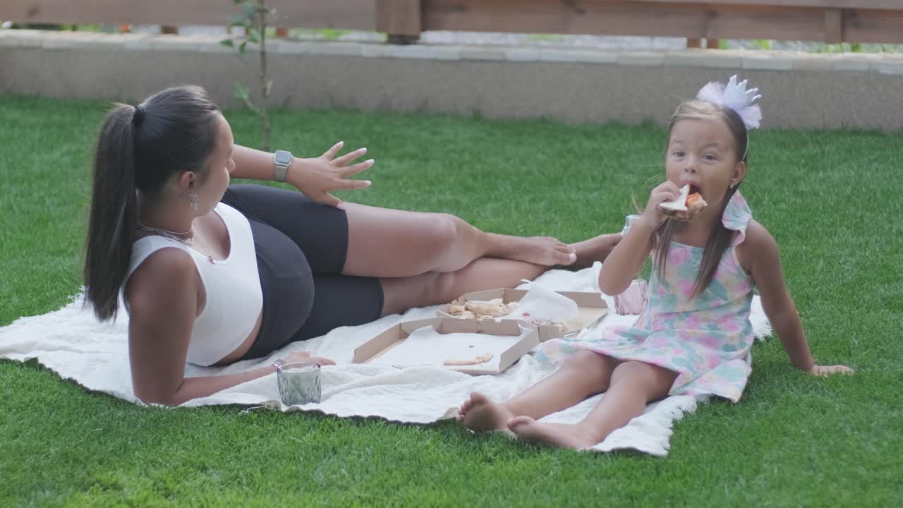 мать и ее маленькая дочь сидят на одеяле на заднем дворе, занимаясь рисованием вместе. сцена на открытом воздухе захватывает мирный семейный момент, способствуя творчеству и связям.