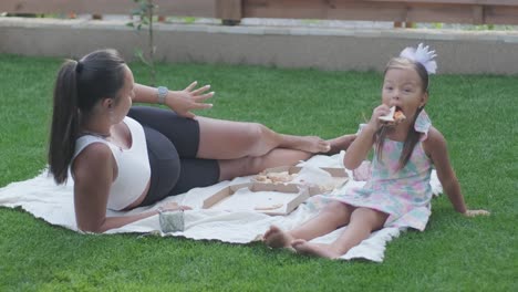 a mother and her young daughter sit on a blanket in the backyard, engaging in a drawing activity together. the outdoor scene captures a peaceful family moment, fostering creativity and bonding.