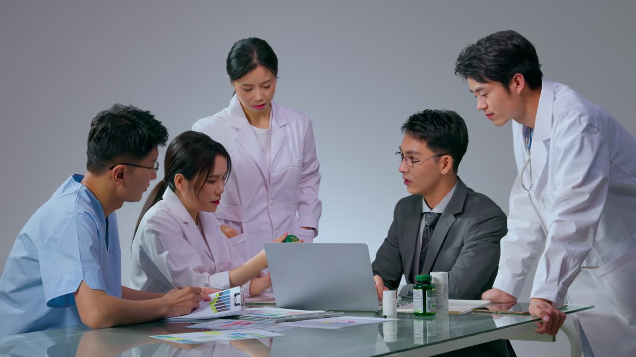 Professional group of doctors and nurses holds a meeting or conference in the hospital, utilizing laptop for healthcare discussions, medical prescription medication. Teamwork commitment to healthcare