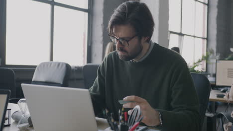 businessman paying bill on laptop in modern office