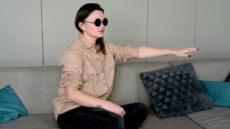 blind woman in sunglasses sitting on sofa at home and petting her cat