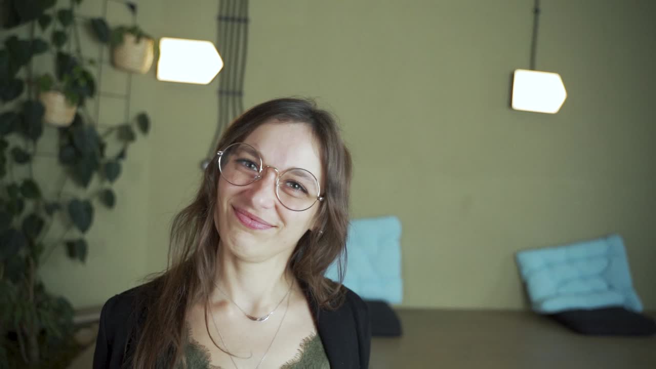 zoom en la cara joven de cabello negro estudiante europea mirando a la cámara diciendo que no decaiga sonriendo y usando ropa elegante y anteojos