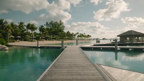 pristine over water cabana bungalows on tropical island on perfect sunny summer day, pull away slow motion