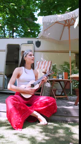 woman playing ukulele outdoors by campervan