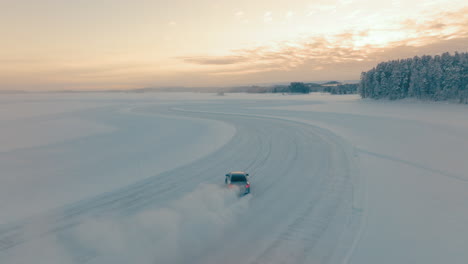 Chasing-driver-drifting-corners-on-Lapland-ice-lake-track-at-sunrise-aerial-view