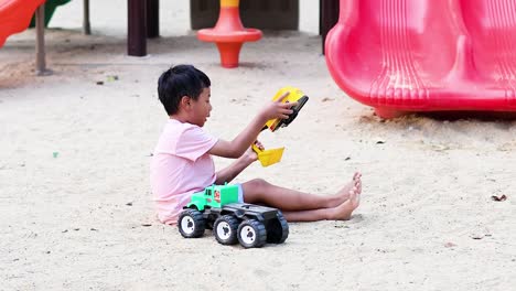 young boy enjoys playing with toy truck and excavator