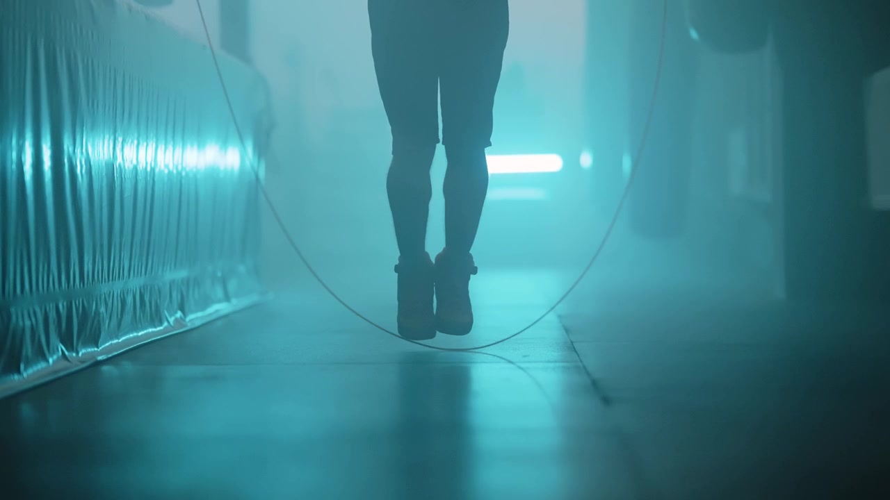 Pernas de Atleta Pulando Corda em uma Academia Escura e Iluminada por Neon.
