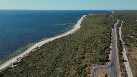 carretera costera y playa de arena con aguas azules claras