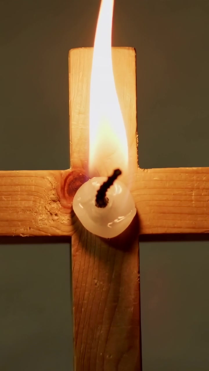 Vertical video: Lit at start, candle on cross flickering, flame growing, wax pooling for light