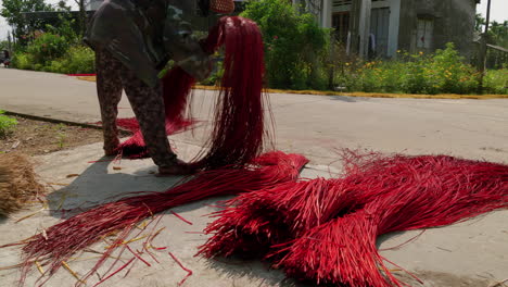 asian woman collecting dried colored straw to be weaved into rug or mattress