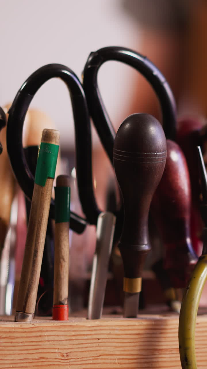 Traditional tools for leather processing on wooden rack in workshop closeup. Skilled craftsman manual instruments kit on table. Handicraft supplies