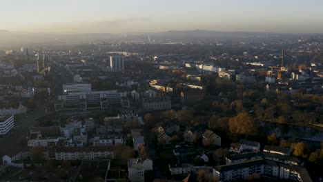 Drohnenaufnahme-Der-Stadtlandschaft-Von-Kassel-In-Schönem,-Weichem-Sonnenlicht-Und-Mit-Nebel-Bedeckt